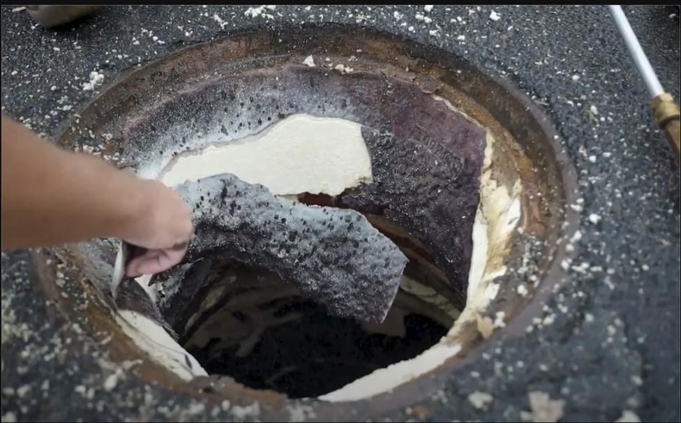 A failed spray-on coating peeling out of a manhole by hand