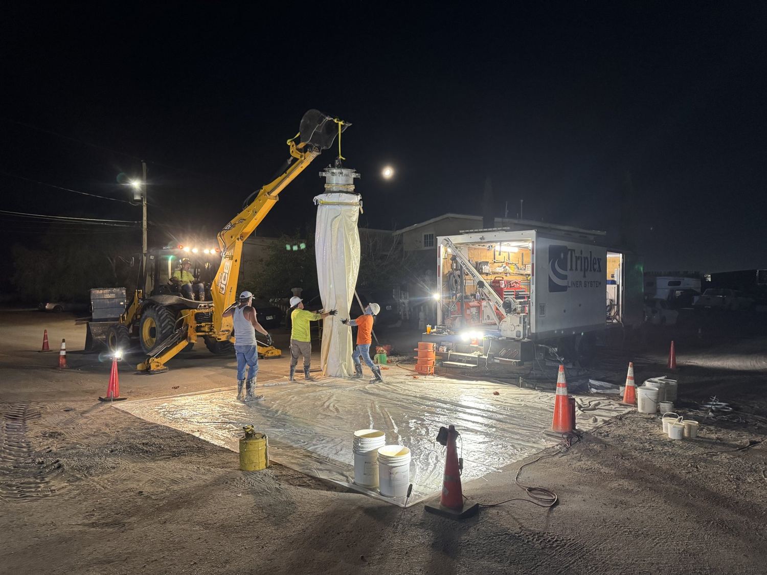 A Triplex crew standing a liner upright under work lights at night